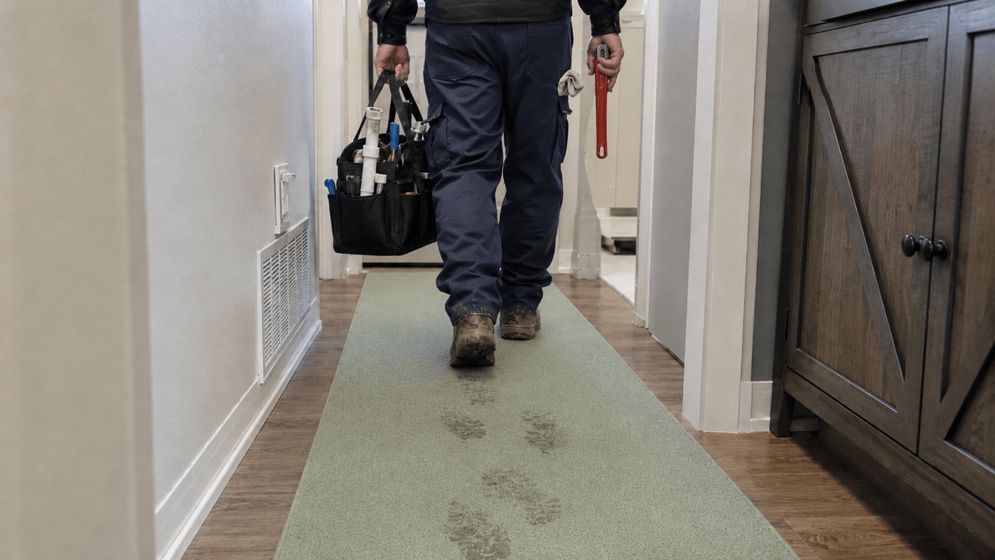 Mokr&eacute; stopy od bot na koberci v chodbě